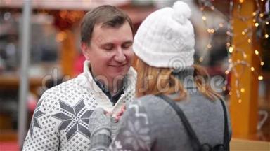 夫妻在圣诞节市场度过了一段有趣的时光，男人笑着和一个女人说话，幸福的年轻家庭。 <strong>祝你快乐</strong>